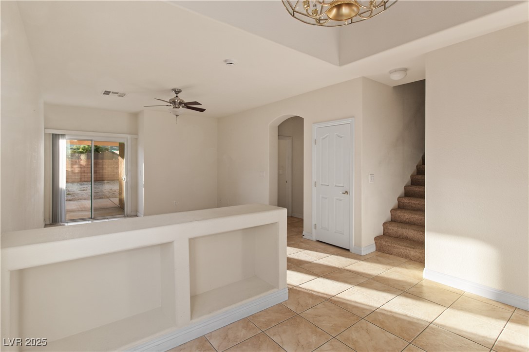 2715 Brinkley Manor Street Laughlin, NV 89029 - Photo 18 of 89 Dining area featuring light tile patterned floors, stairway to upstairs loft and bedrooms, and arched walkway downstairs to Primary Bedroom
