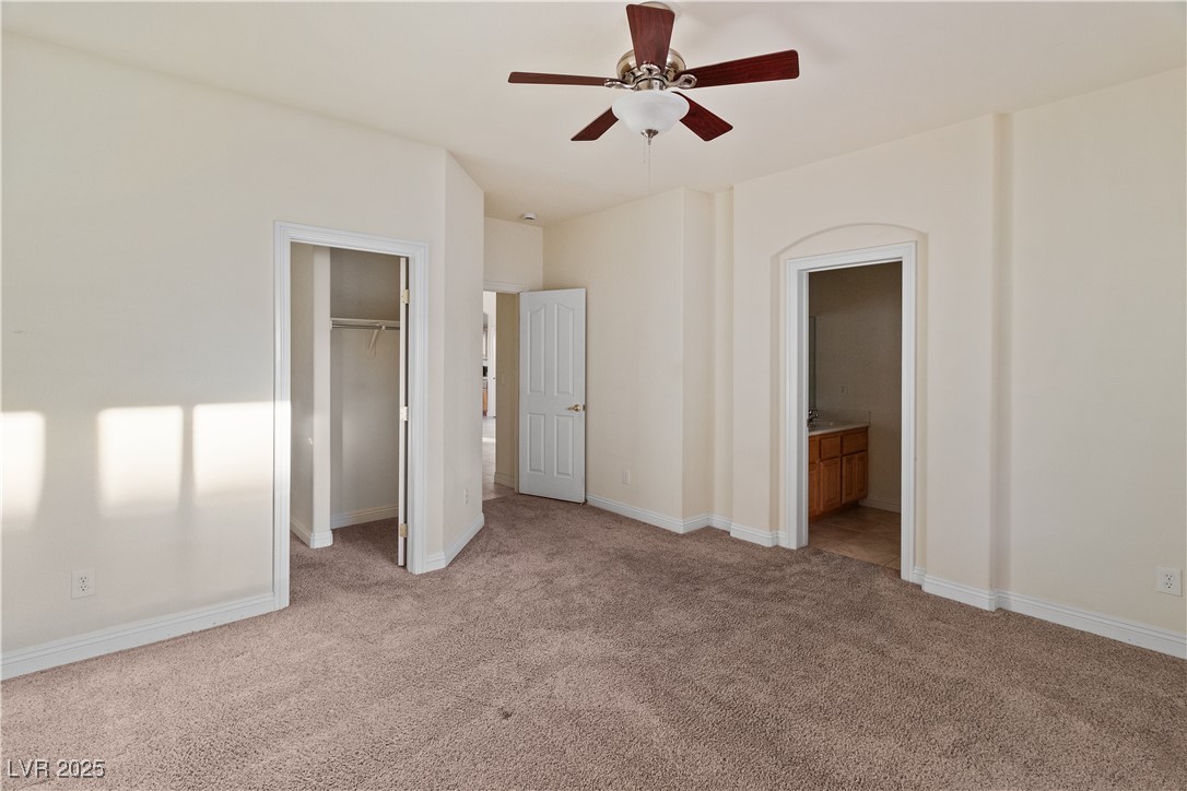 2715 Brinkley Manor Street Laughlin, NV 89029 - Photo 24 of 89 Primary Bedroom with a spacious closet, light colored carpet, ensuite bathroom, and ceiling fan