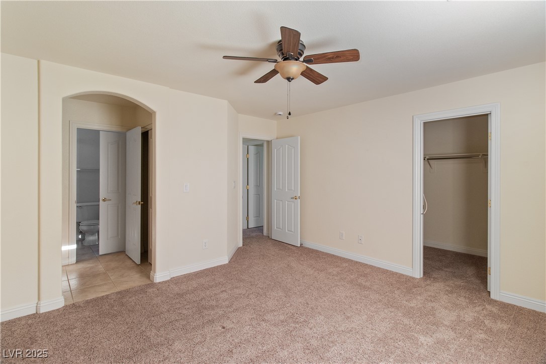 2715 Brinkley Manor Street Laughlin, NV 89029 - Photo 33 of 89 Second bedroom featuring a spacious closet, light carpet, arched walkways, and a ceiling fan