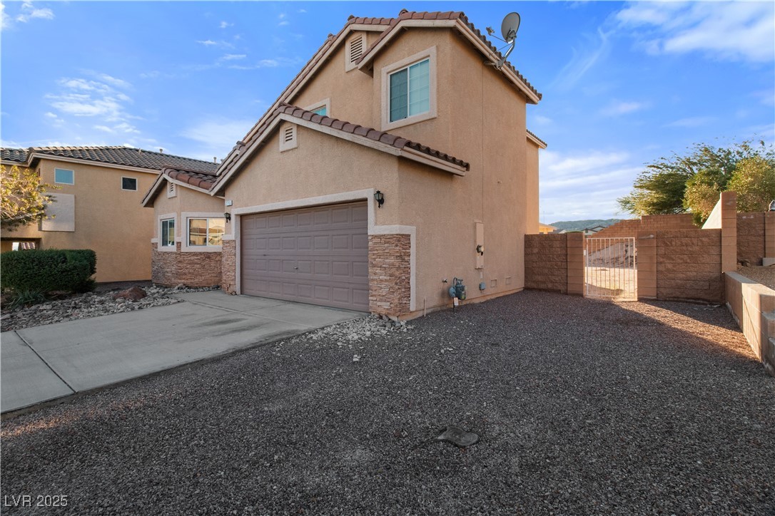 2715 Brinkley Manor Street Laughlin, NV 89029 - Photo 52 of 89 View of property exterior featuring a gate, stucco siding, driveway, a garage, and a tile roof