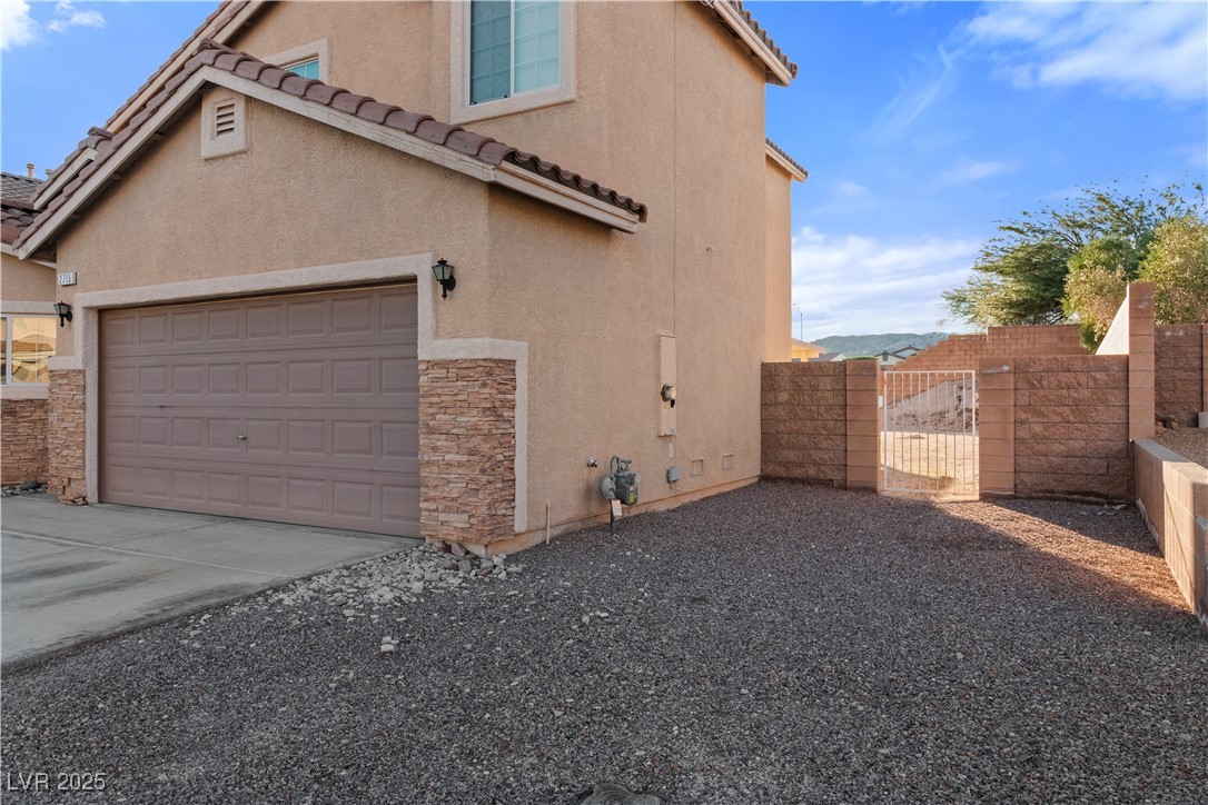 2715 Brinkley Manor Street Laughlin, NV 89029 - Photo 53 of 89 View of side of property featuring a gate, a tiled roof, stucco siding, stone siding, and concrete driveway