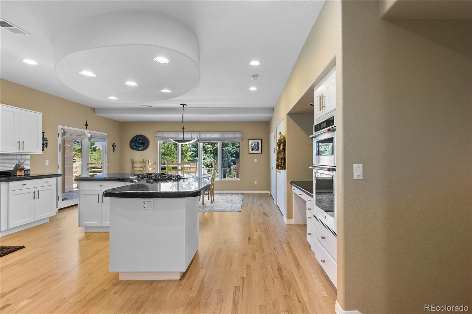 69 North Ranch Road Littleton, CO 80127 - Photo 15 of 50 a view of a kitchen with kitchen island a counter top space a sink and wooden floor