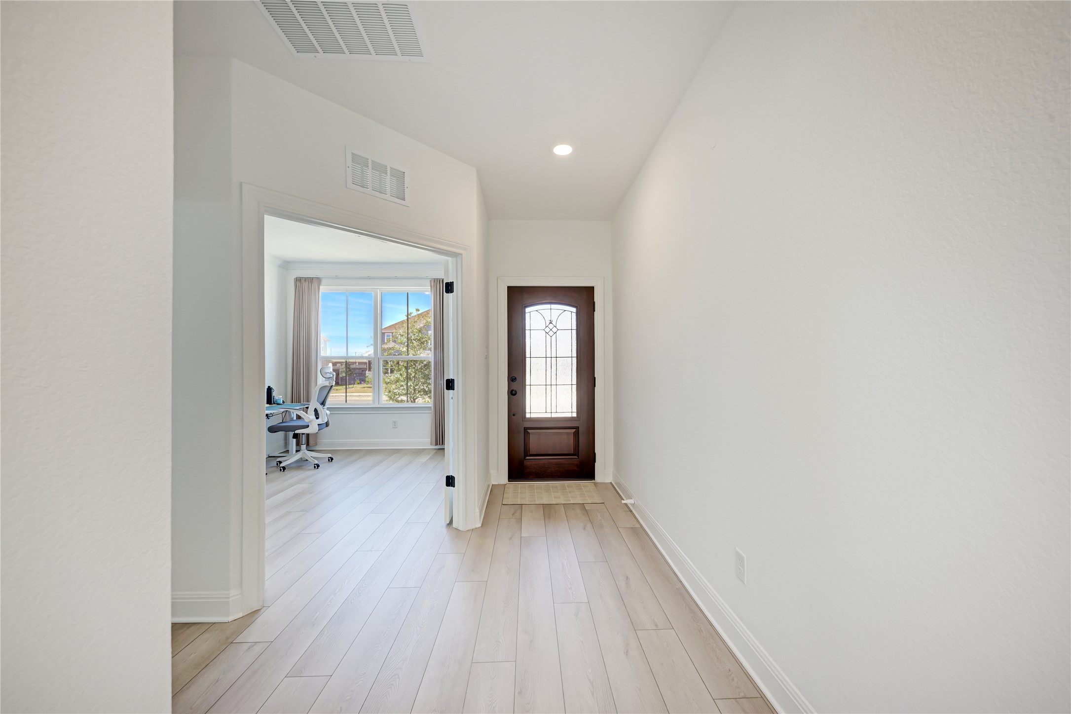 316 Regatta Trail Leander, TX 78641 - Photo 3 of 39 Entryway featuring light wood-finish flooring, a dark wood-paneled front door with decorative glass, recessed lighting, and white baseboards