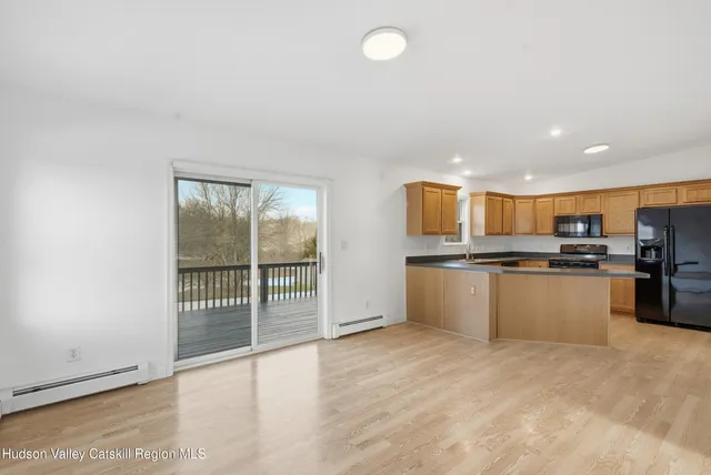 a kitchen with stainless steel appliances granite countertop a refrigerator a stove top oven a sink dishwasher and chairs with wooden floor