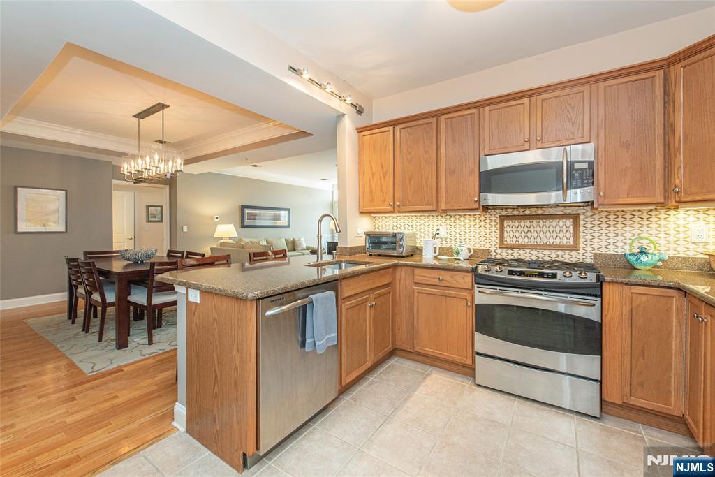 6105 Harcourt Road Clifton, NJ 07013 - Photo 10 of 23 a kitchen with stainless steel appliances granite countertop a stove top oven a sink dishwasher a dining table and chairs with wooden floor