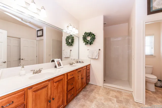 a spacious bathroom with a double vanity sink toilet and shower