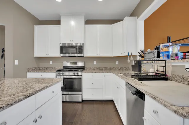 a kitchen with stainless steel appliances granite countertop a refrigerator a stove and a sink