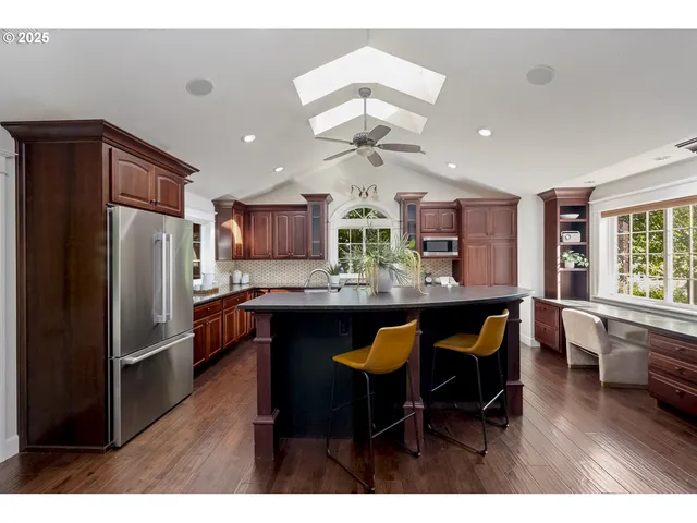 a kitchen with stainless steel appliances granite countertop a refrigerator a sink dishwasher a dining table and chairs with wooden floor