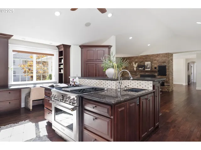 a kitchen with stainless steel appliances granite countertop a stove a sink dishwasher and cabinets with wooden floor