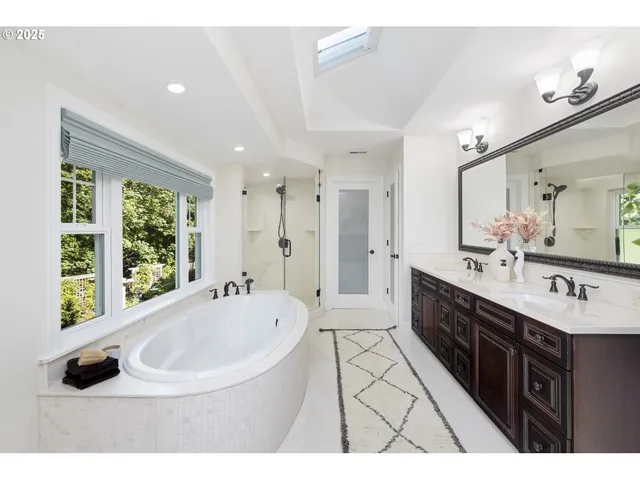 a bathroom with a double vanity sink a bathtub and a window