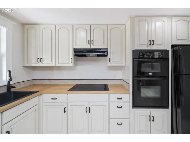 a kitchen with white cabinets and refrigerator