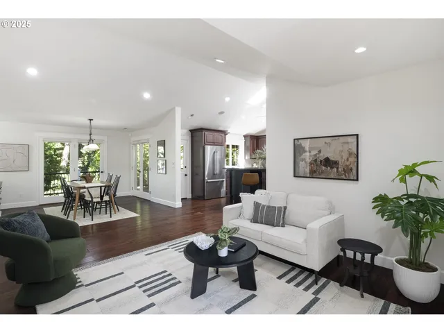 a living room with furniture potted plant and kitchen view