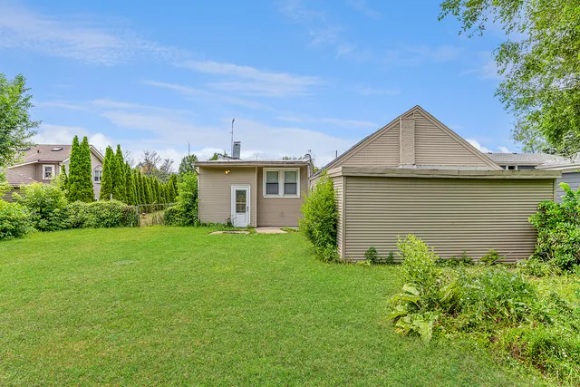 a backyard of a house with plants and large tree