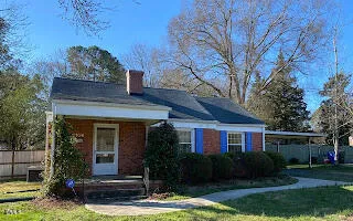 a view of a brick house with a yard potted plants and large tree