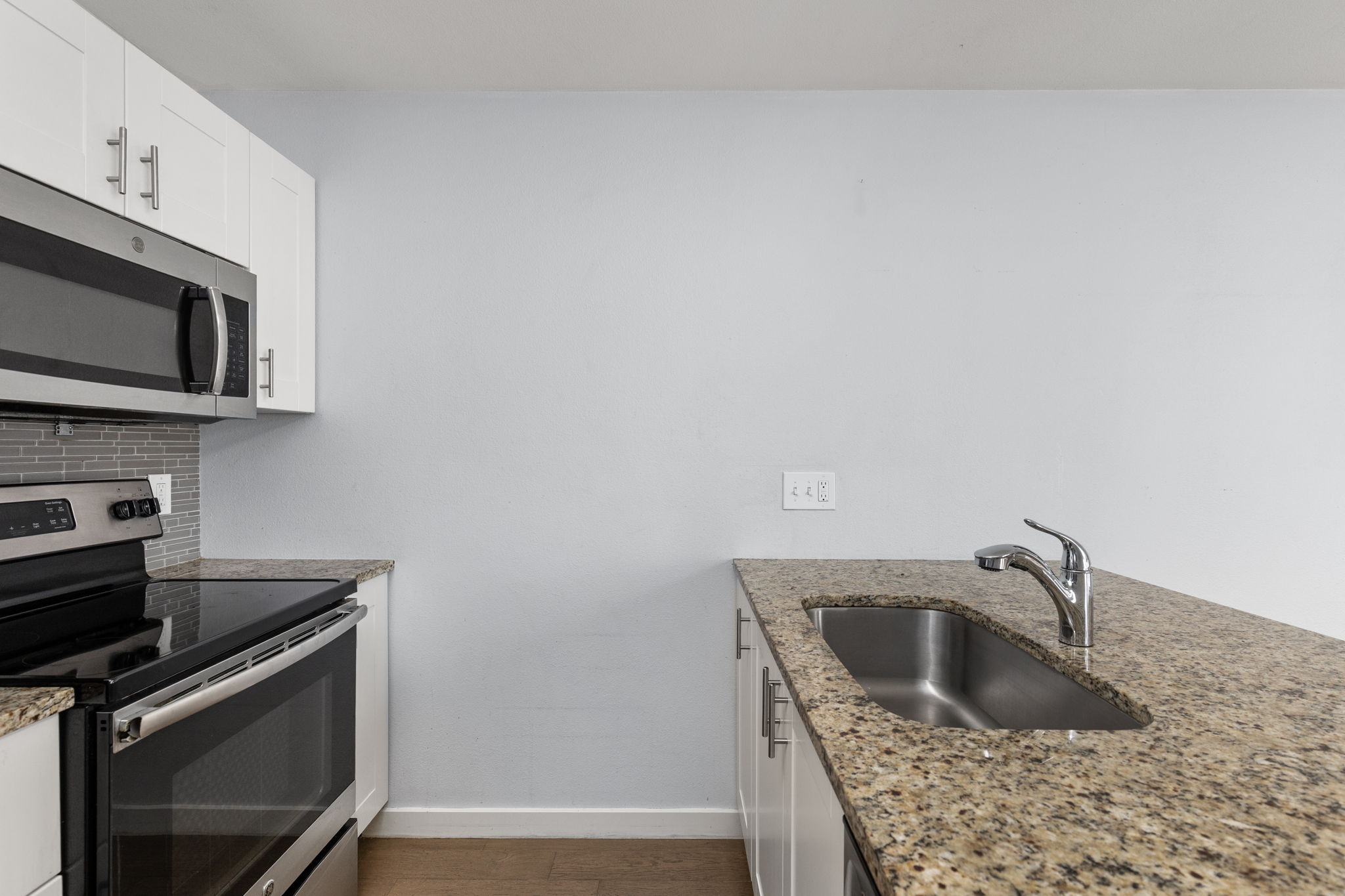 909 Reinli Street, Unit 232 Austin, TX 78751 - Photo 8 of 13 a kitchen with granite countertop a sink dishwasher stove and microwave with wooden floor