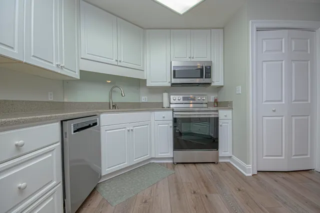 a kitchen with granite countertop white cabinets and stainless steel appliances