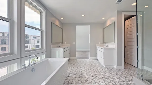 a bathroom with a tub a sink a mirror and a shower