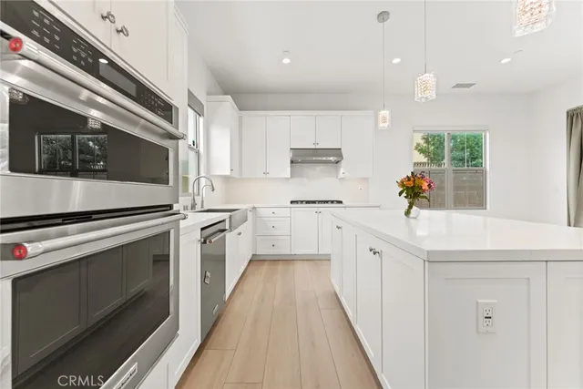 a kitchen with a sink a stove oven and white cabinets