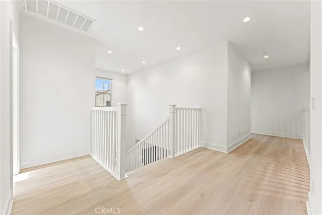 a view of a hallway with wooden floor and a bathroom