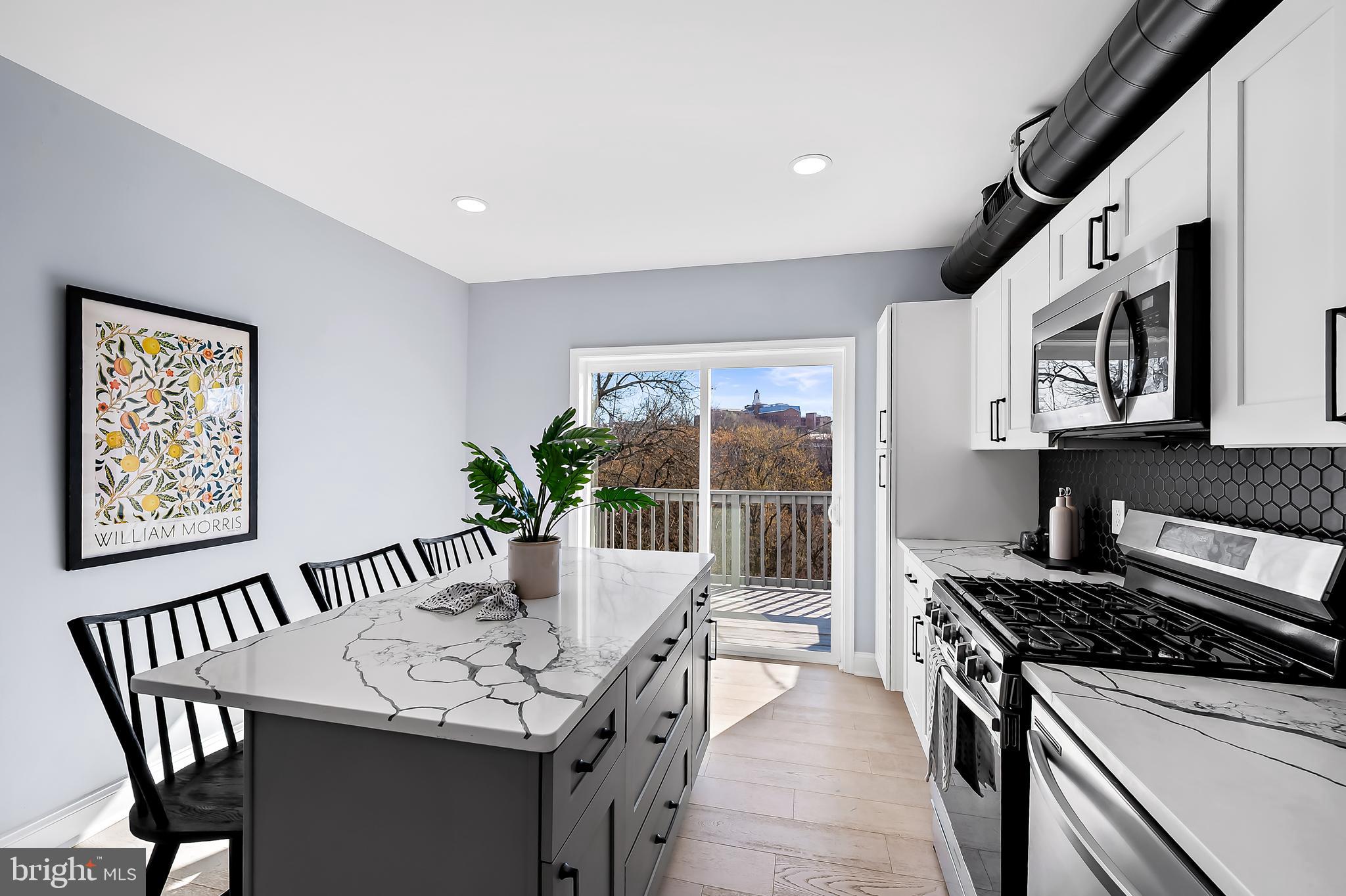 3137 Keswick Road Baltimore, MD 21211 - Photo 7 of 31 a kitchen with stainless steel appliances granite countertop a stove a sink a microwave dining table and chairs