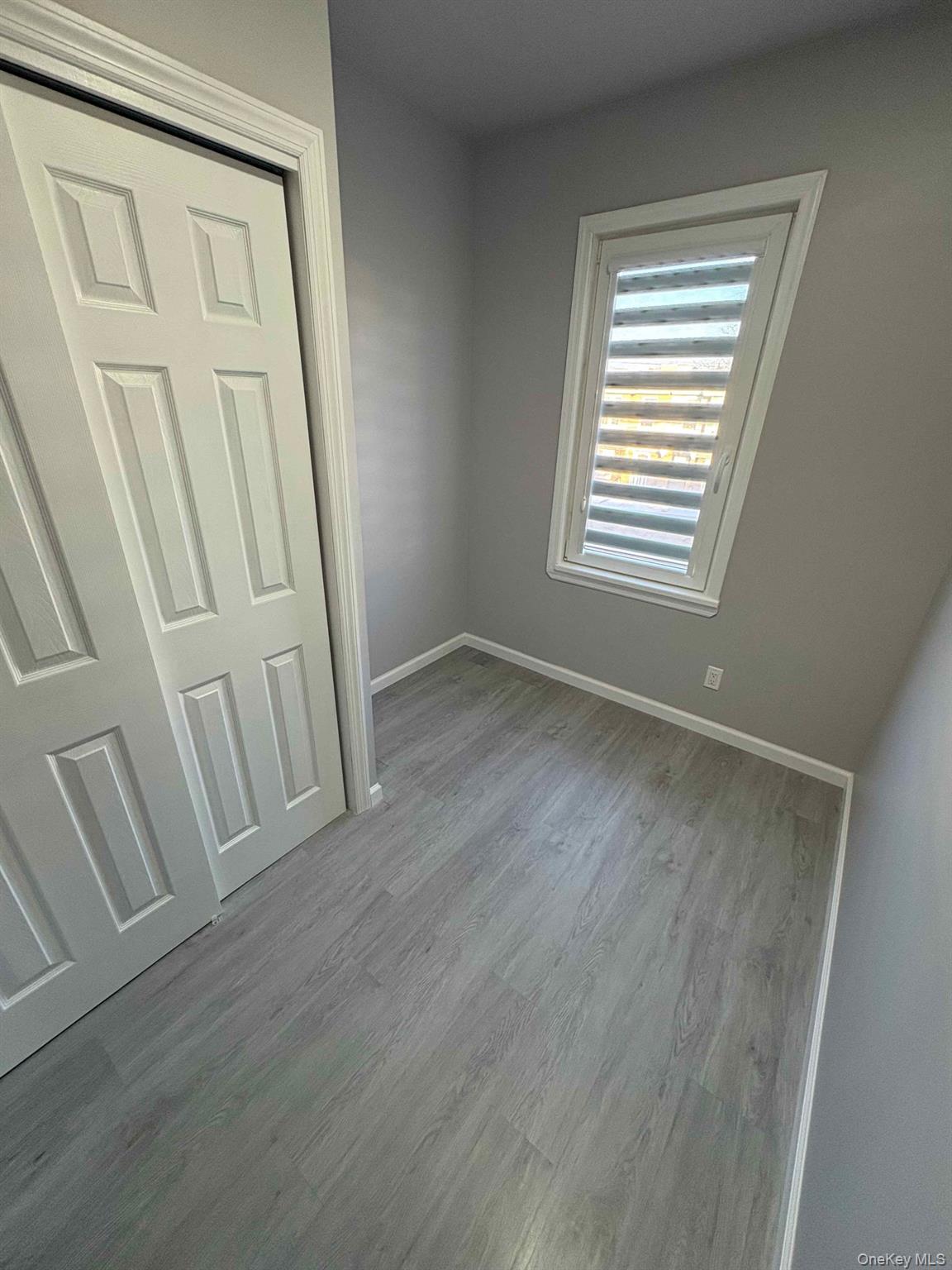 58-46 Fresh Pond Road, Unit 2 Queens, NY 11378 - Photo 7 of 9 an empty room with wooden floor and windows