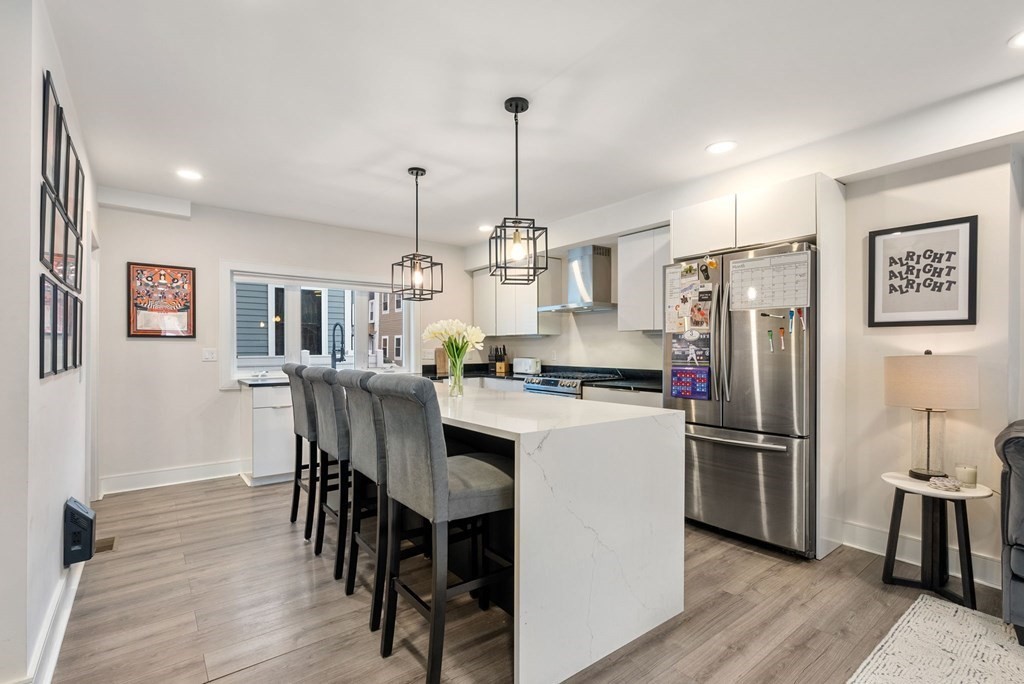 a kitchen with stainless steel appliances a dining table chairs refrigerator and cabinets