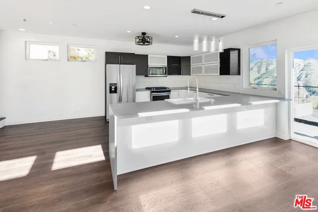a large kitchen with stainless steel appliances a large counter top and a wooden floor
