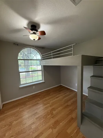 an empty room with wooden floor cabinet and windows