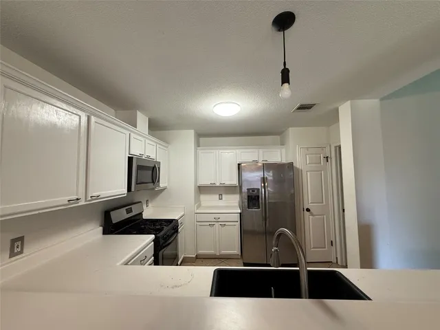 a kitchen with stainless steel appliances a sink a stove a microwave a refrigerator a counter space and cabinets