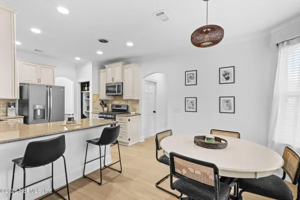 a kitchen with stainless steel appliances granite countertop a sink a stove a refrigerator a dining table and chairs with wooden floor