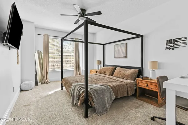 a bedroom with a bed flat screen tv and a window