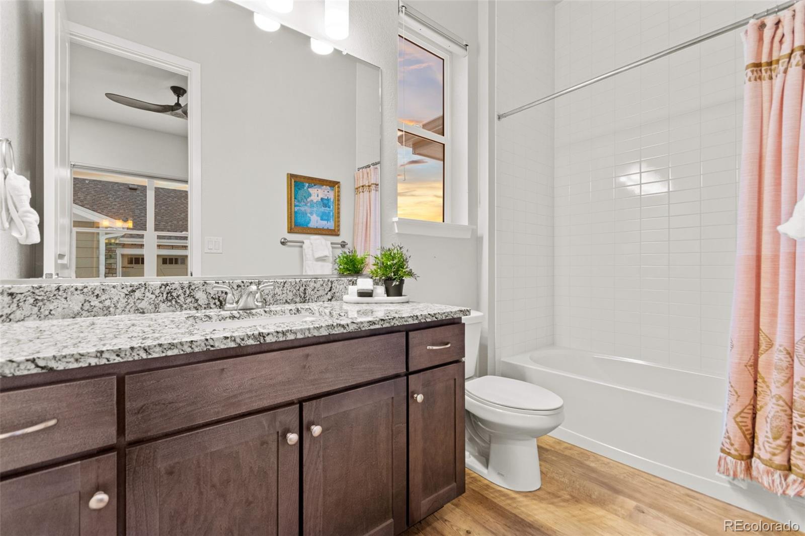 9388 Dunraven Loop Arvada, CO 80007 - Photo 31 of 50 a bathroom with a granite countertop toilet a sink and a mirror