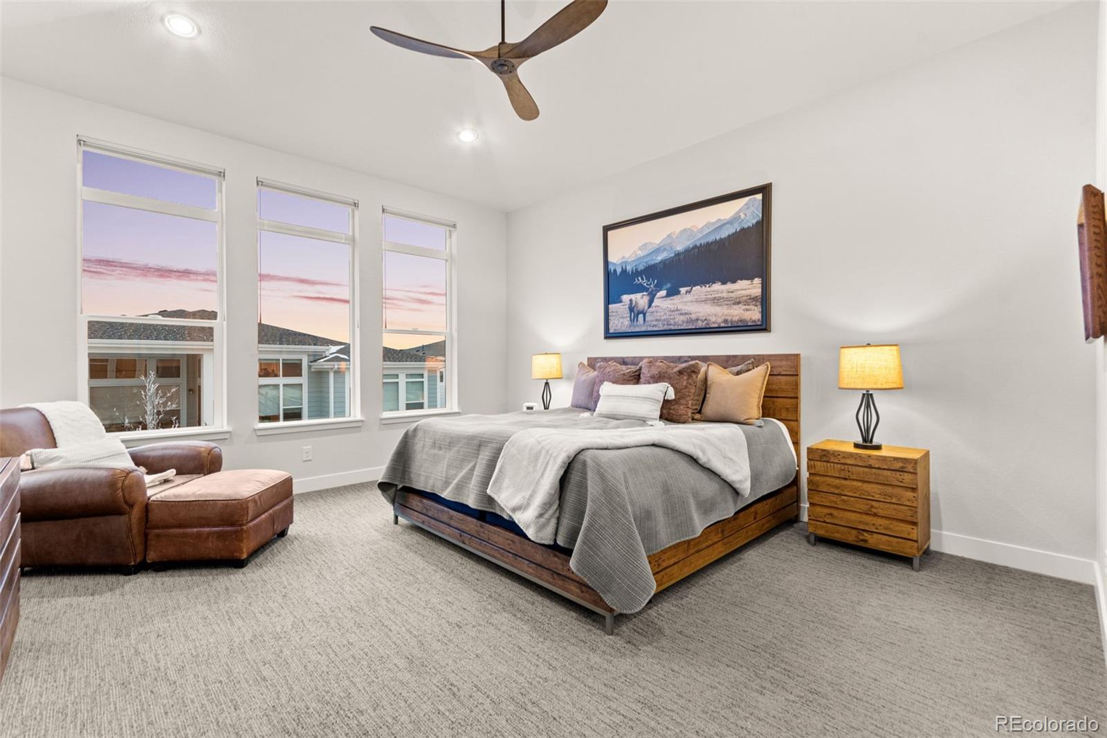 9388 Dunraven Loop Arvada, CO 80007 - Photo 32 of 50 a spacious bedroom with a bed a couch and a large window