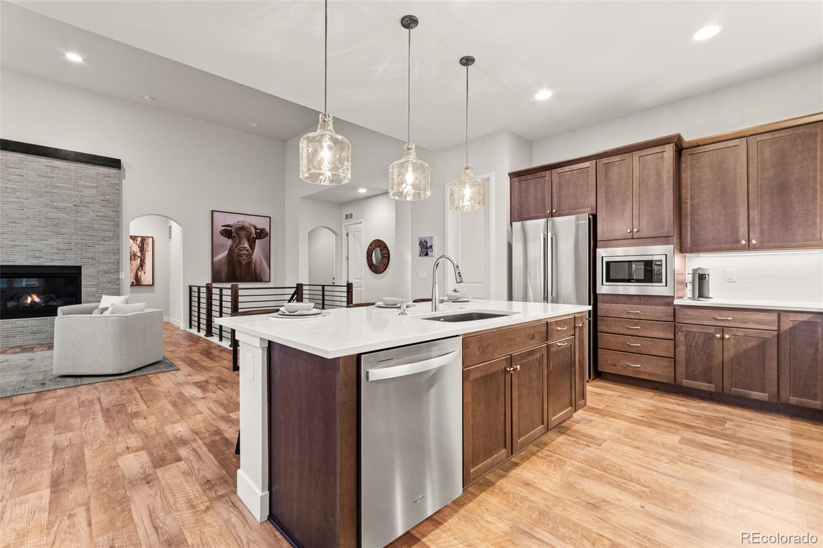 9388 Dunraven Loop Arvada, CO 80007 - Photo 10 of 50 a kitchen with kitchen island granite countertop a stove a sink a refrigerator and a wooden cabinets