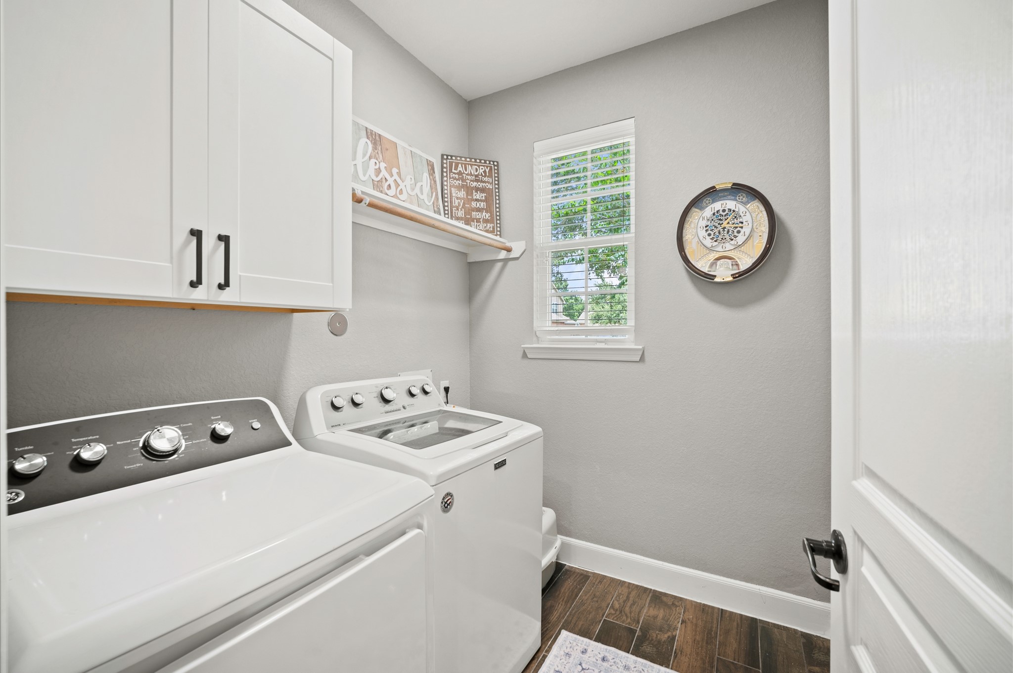 9507 Empress Crossing Drive Spring, TX 77379 - Photo 21 of 50 This laundry room features modern appliances, white cabinetry, and natural light from a window. It has a clean, organized look with a shelf for decor and essentials, plus wood-style flooring for a polished finish.