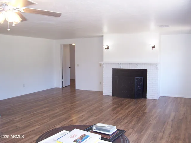 a view of empty room with wooden floor and fireplace