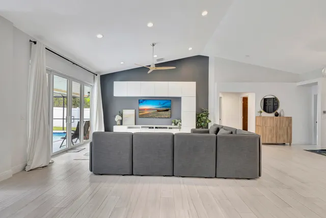 a living room with furniture a flat screen tv and a floor to ceiling window