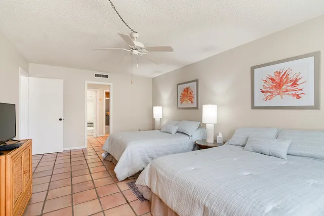 a bedroom with two beds and a lamp on the dresser