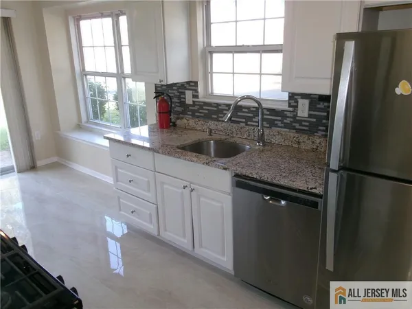 a kitchen with stainless steel appliances granite countertop a refrigerator sink and window