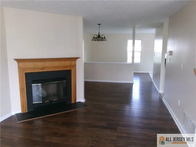 a view of an empty room with wooden floor fireplace and a window