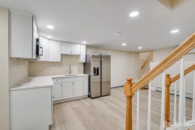 a kitchen with a sink a refrigerator and white cabinets
