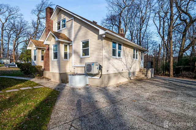 a view of a white house with a yard and lawn chairs next to a yard