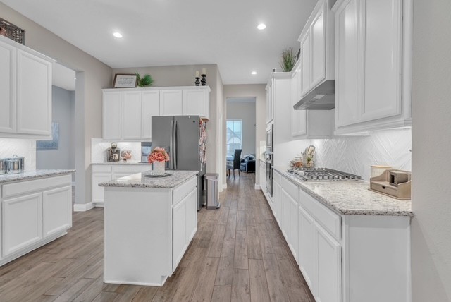 1541 North Blue Bonnet Lane Angleton, TX 77515 - Photo 8 of 28 a kitchen with granite countertop a sink stove refrigerator and white cabinets with wooden floor