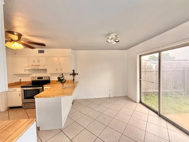 a large white kitchen with a stove a sink dishwasher and a refrigerator with wooden floor