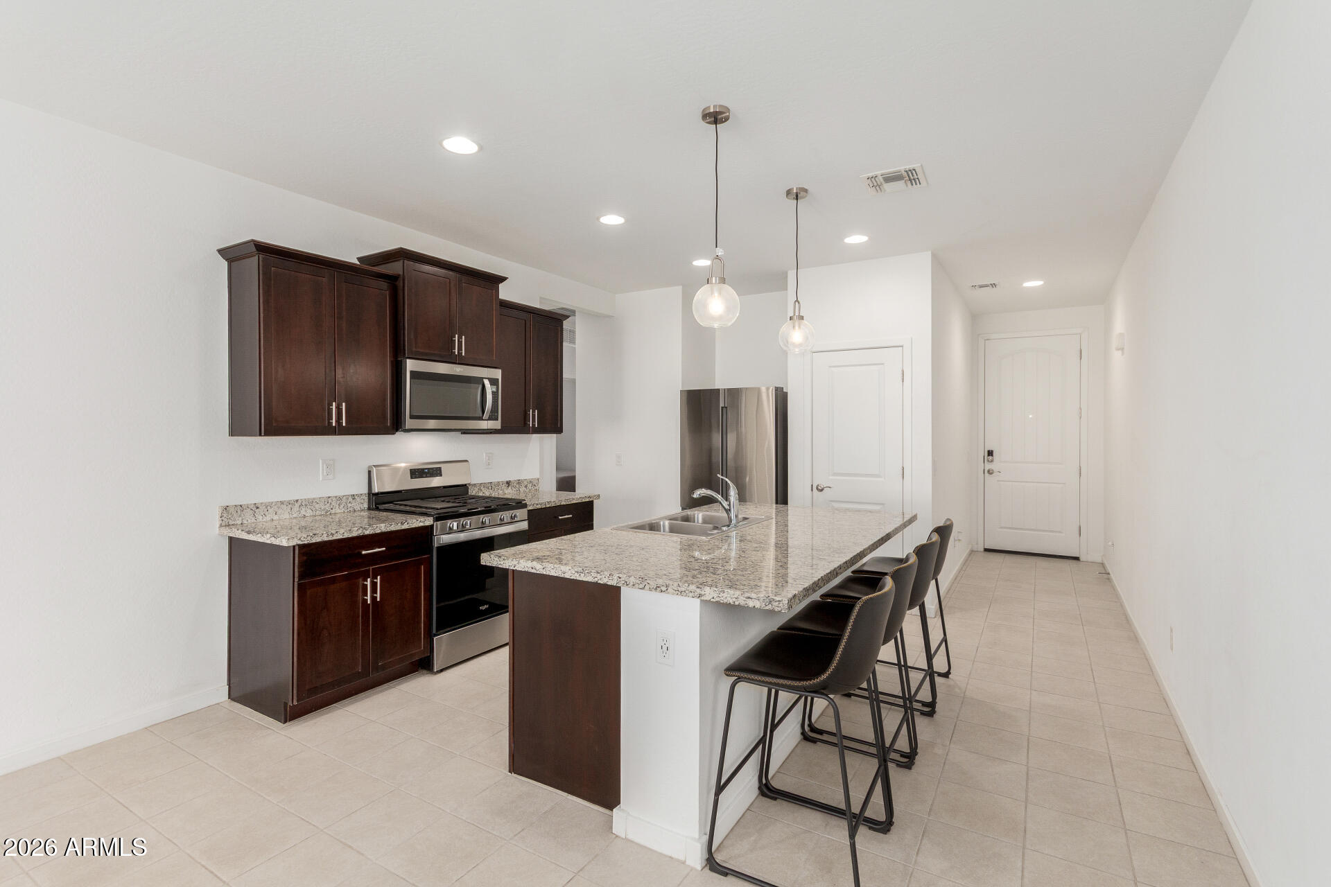 10734 West Bloch Road Tolleson, AZ 85353 - Photo 6 of 20 a kitchen with stainless steel appliances kitchen island granite countertop a stove a sink a refrigerator and a microwave