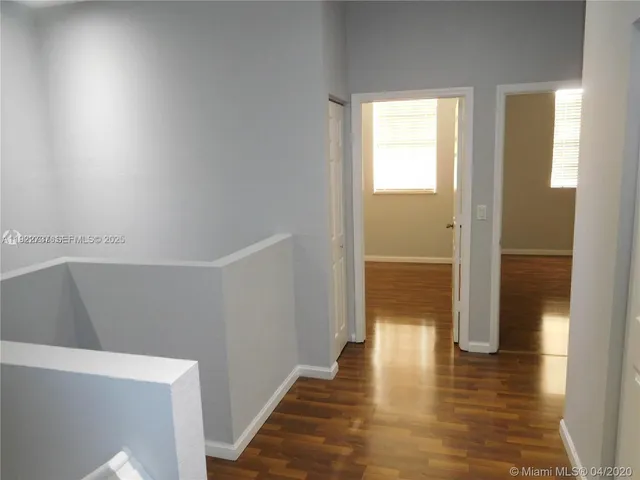 a view of a hallway with wooden floor and a bathroom