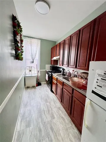 a kitchen with stainless steel appliances granite countertop a stove a sink dishwasher and a refrigerator with wooden floor