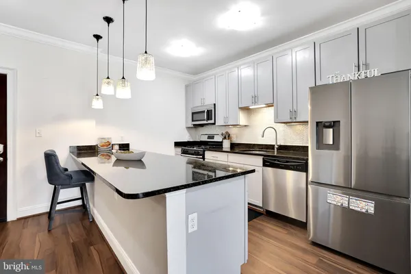 a kitchen with stainless steel appliances granite countertop a sink a stove a refrigerator and island with wooden floor