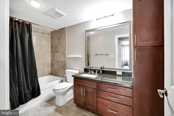 a bathroom with a granite countertop sink toilet a mirror and shower