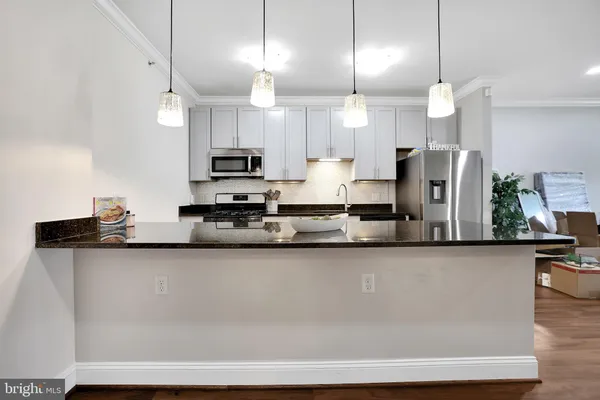 a large kitchen with granite countertop a sink a counter space stainless steel appliances and cabinets